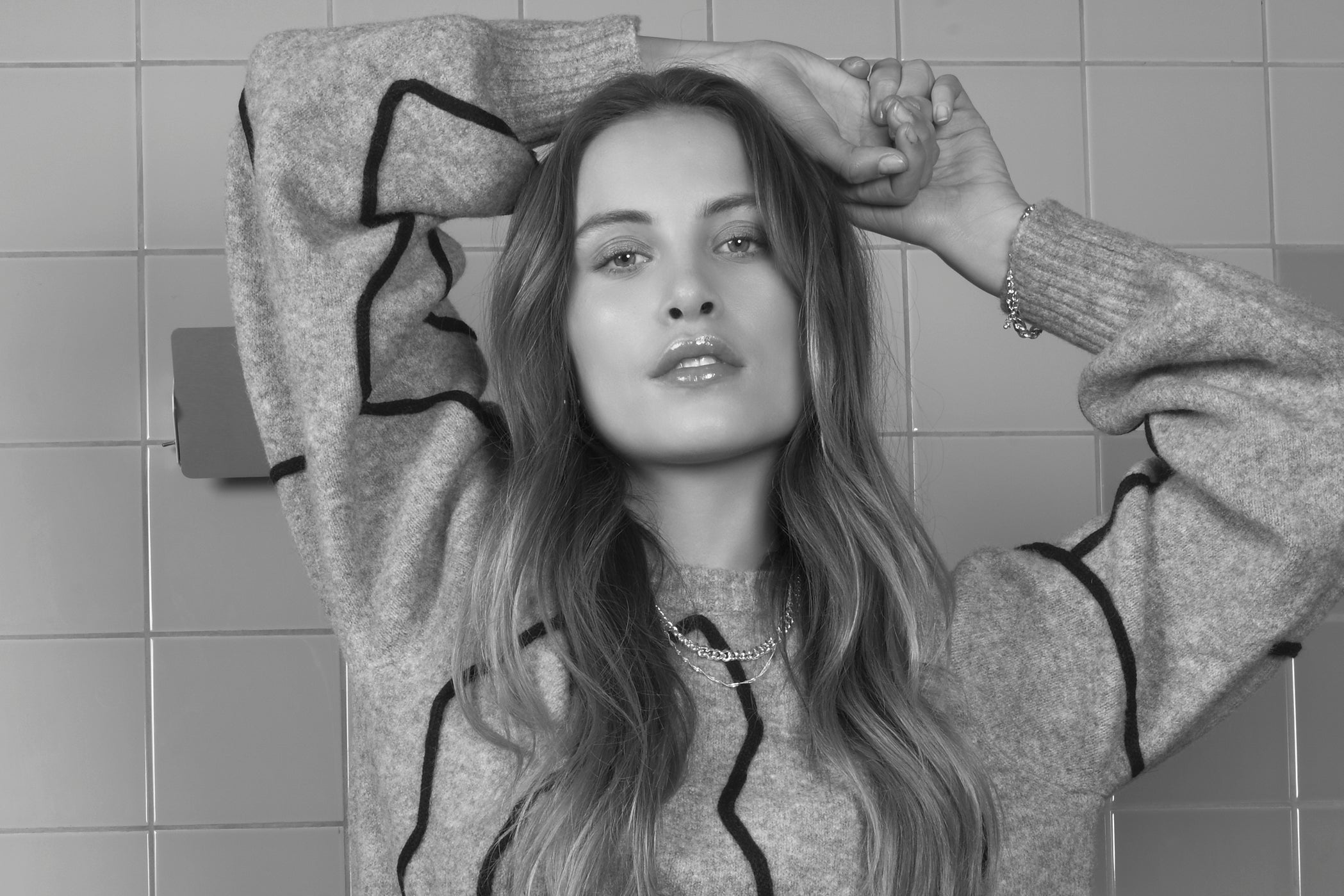 Een vrouw draagt een grijze trui met zwart patroon.